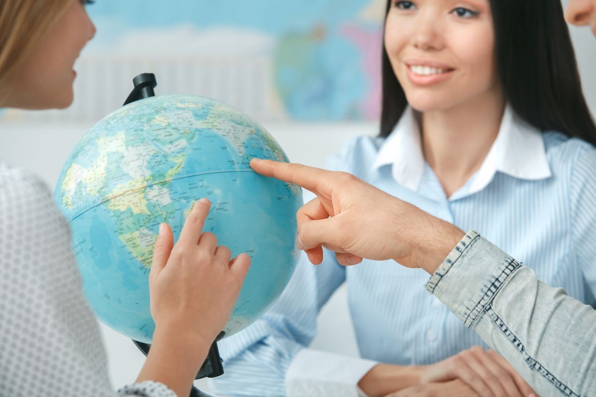 Young couple in a tour agency communication with a travel agent travelling concept globe choosing destination close-up